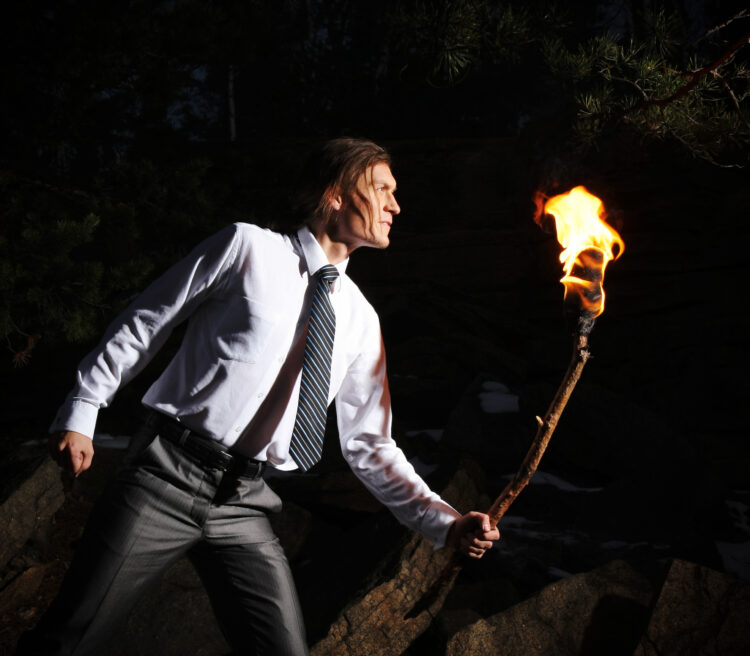 man with burning stick while moving in darkness