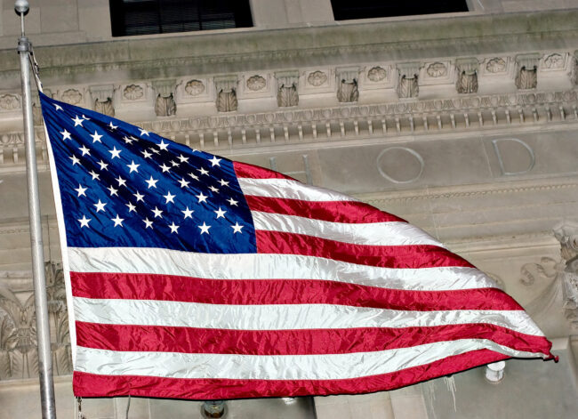 An American flag flying in front of some classic architecture.